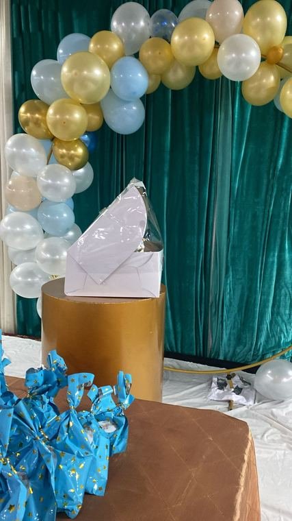 Gold, pearl and pale blue balloon garland on a round arch frame above a gift table